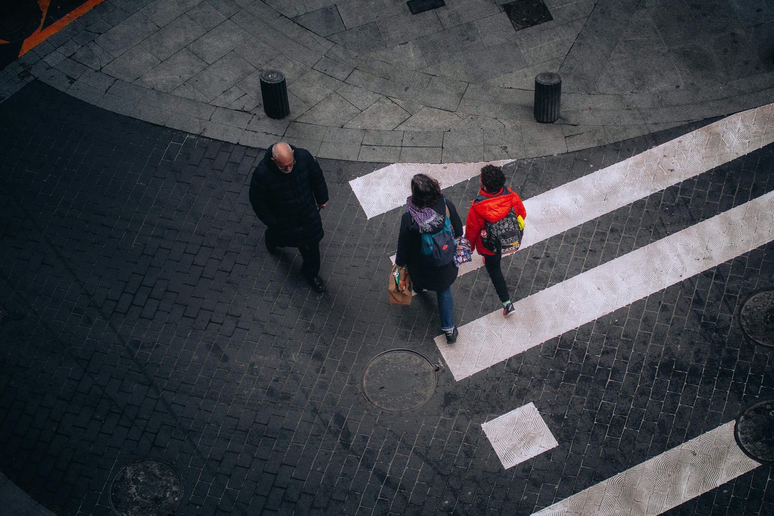 High-angle view of people crossing a street in Bilbao, Spain, showcasing urban life.